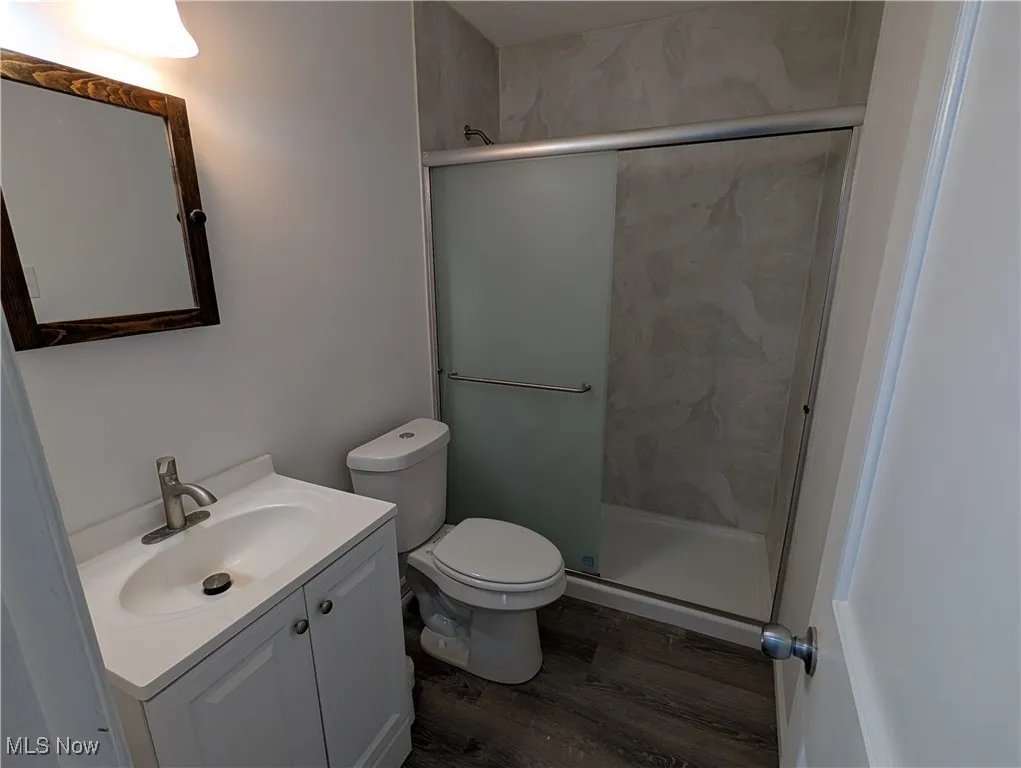 Bathroom with vanity, a marble finish shower, and dark wood-style floors