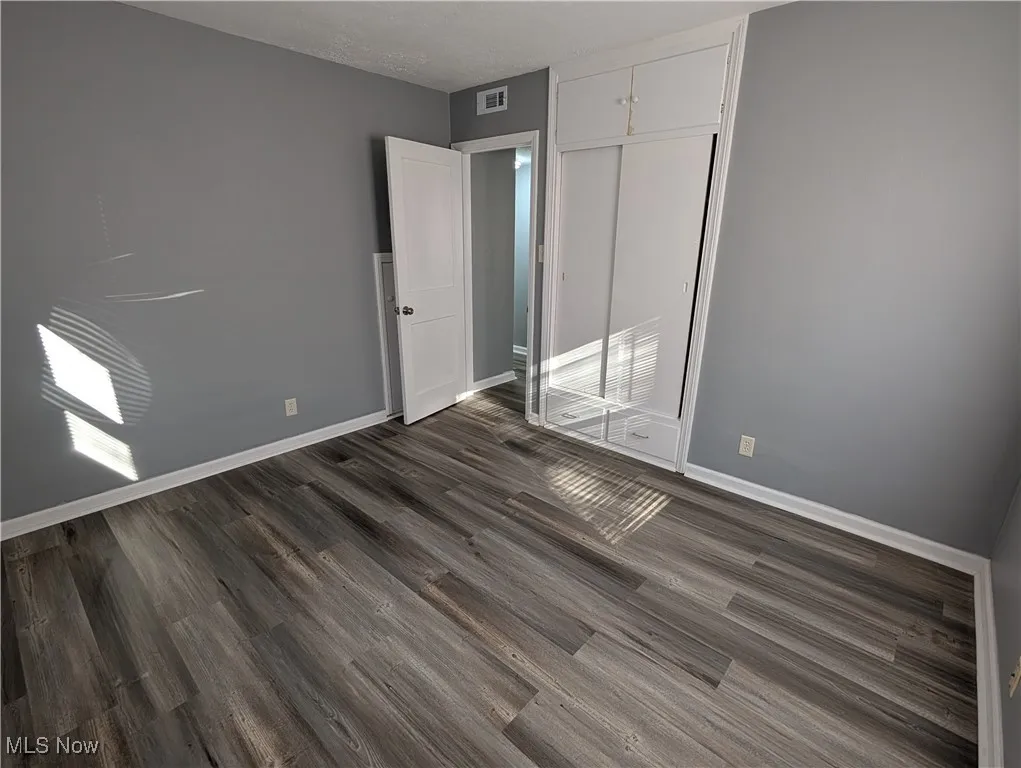 First floor bedroom featuring dark wood-type flooring and a closet