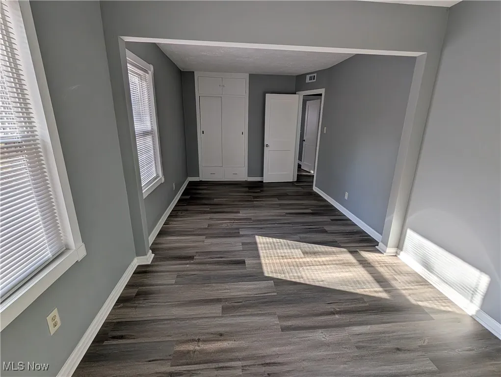 Primary bedroom on first floor featuring dark wood-type flooring, a closet, and a textured ceiling