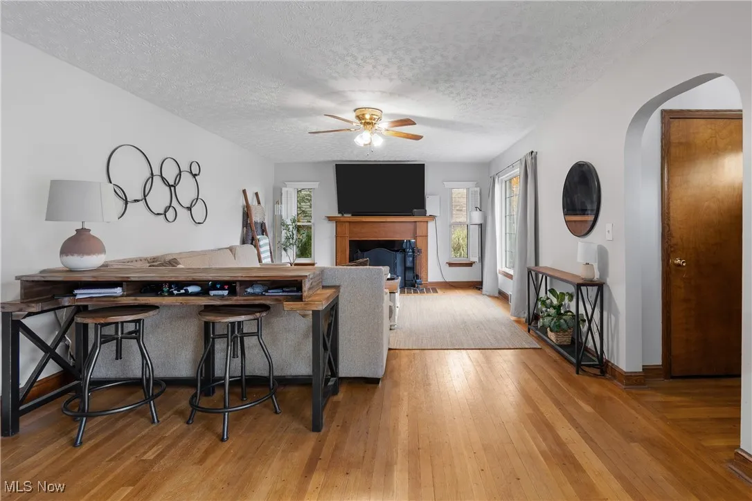 Dining space with a textured ceiling, arched walkways, light wood-type flooring, and ceiling fan