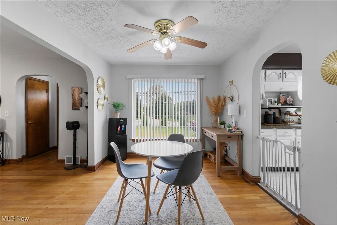 Living area featuring a textured ceiling, wood finished floors, a fireplace with flush hearth, and a ceiling fan, hardwood floors