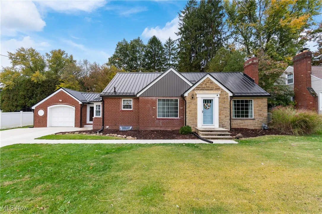 Cape Cod-style house with concrete driveway, a metal roof, a garage, a standing seam roof, and brick siding