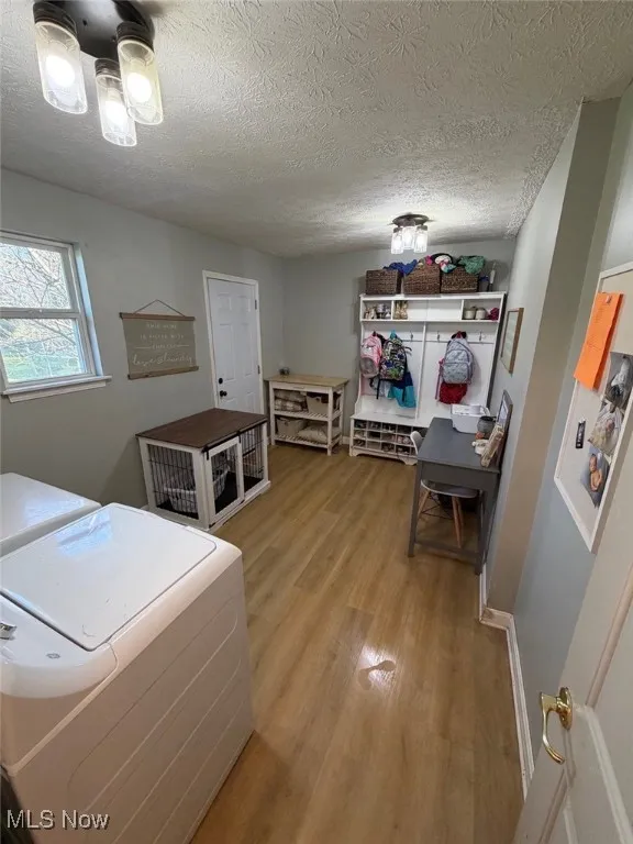 Laundry area with light wood finished floors, a textured ceiling, and independent washer and dryer