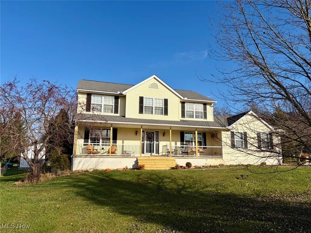View of front of house with covered porch, a front lawn, and a shingled roof
