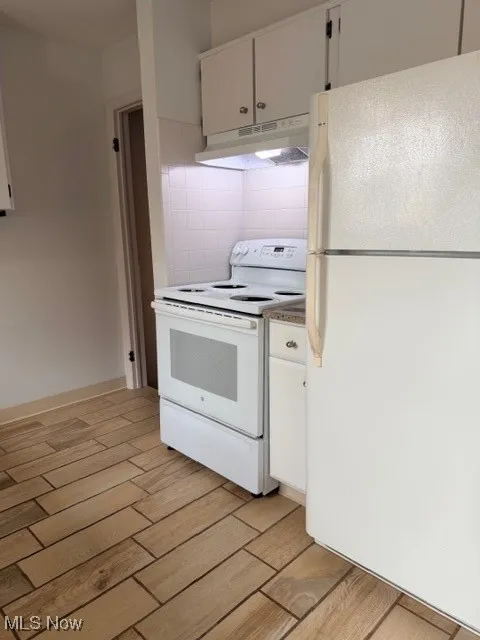 Kitchen with refrigerator, electric stove, light wood finished floors, and white cabinets