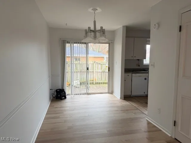 Unfurnished dining area featuring a chandelier and light wood finished floors