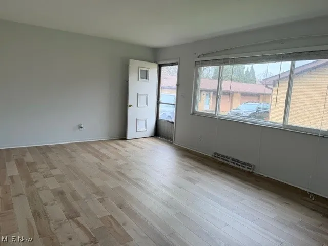 Unfurnished room featuring light wood finished floors and baseboards