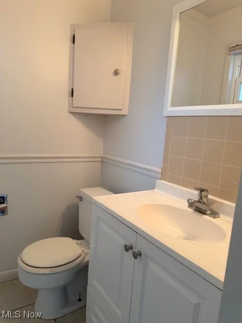 Half bath with vanity, light tile patterned floors, and backsplash