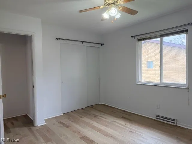Unfurnished bedroom featuring a ceiling fan, light wood finished floors, and a closet
