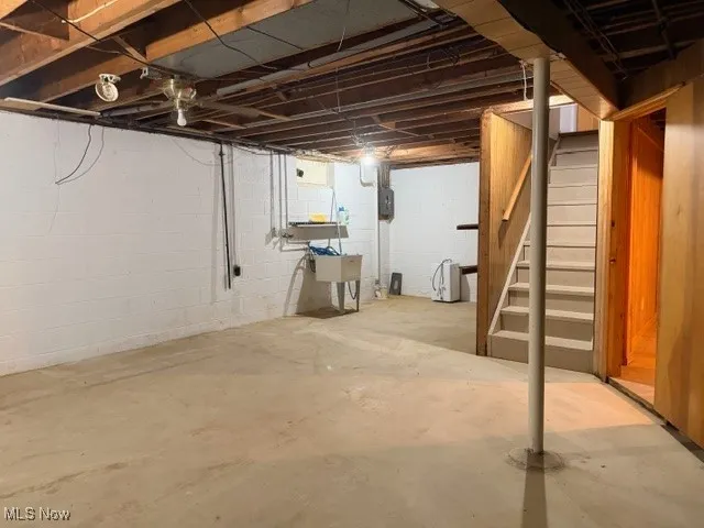 Unfinished basement with stairs and electric panel