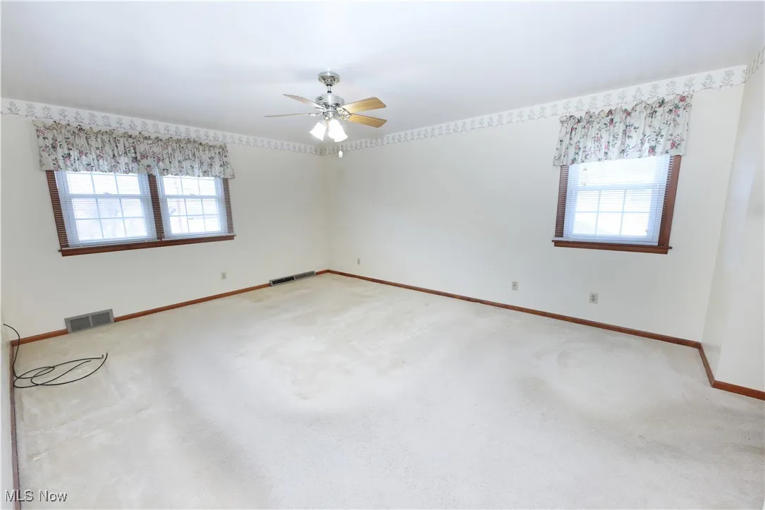 Carpeted spare room with baseboards and ceiling fan