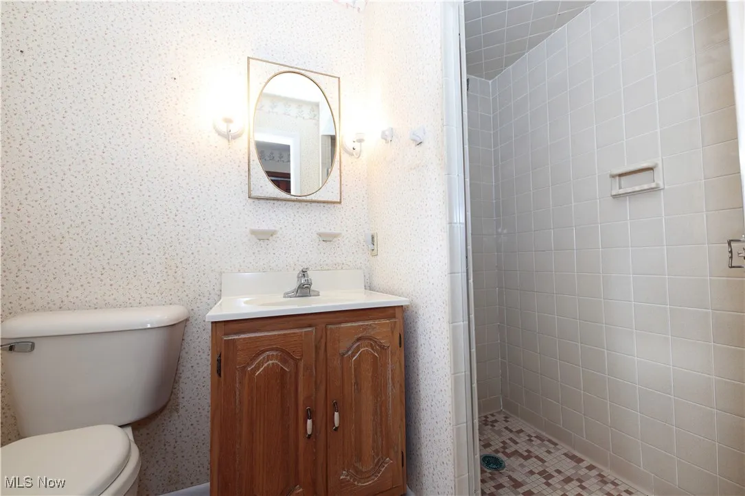 Bathroom with vanity, a stall shower, and wallpapered walls
