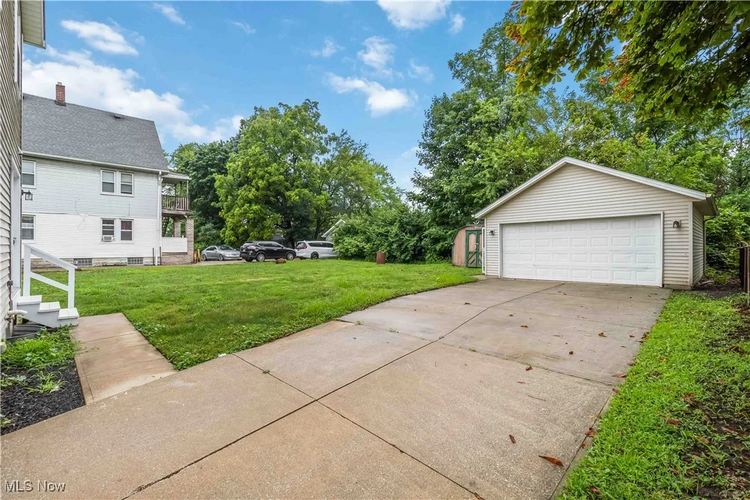View of green lawn with an outdoor structure and a garage