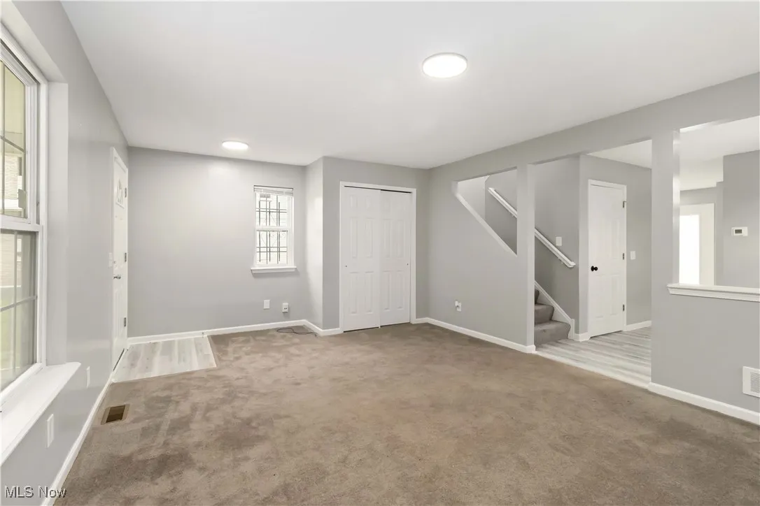 Unfurnished room with stairway and light colored carpet