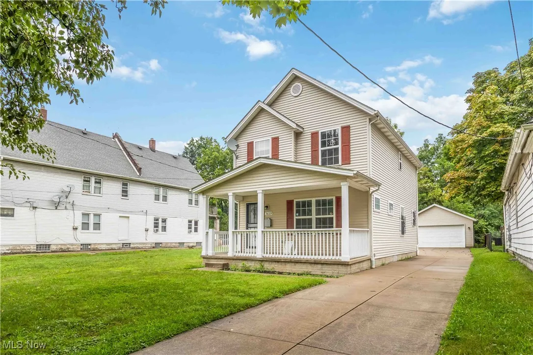 View of front facade with covered porch, a front yard, a garage, and an outdoor structure