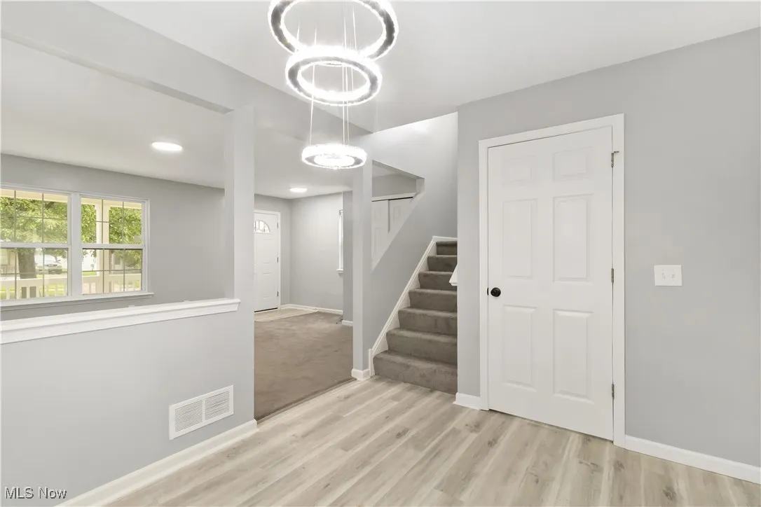 Staircase with wood finished floors, recessed lighting, and a chandelier
