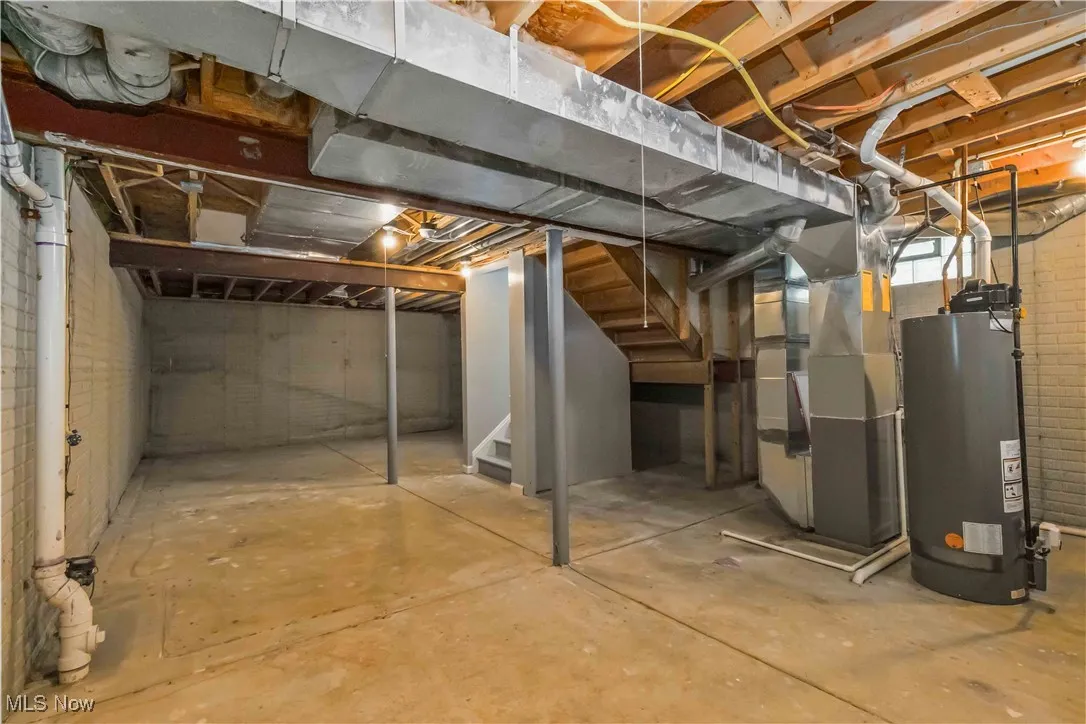 Unfinished below grade area featuring stairs, water heater, and heating unit