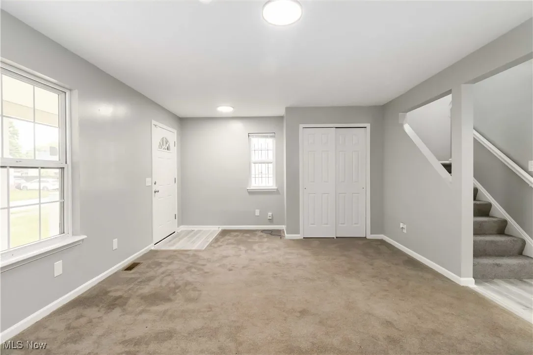 Carpeted foyer entrance featuring stairway and baseboards