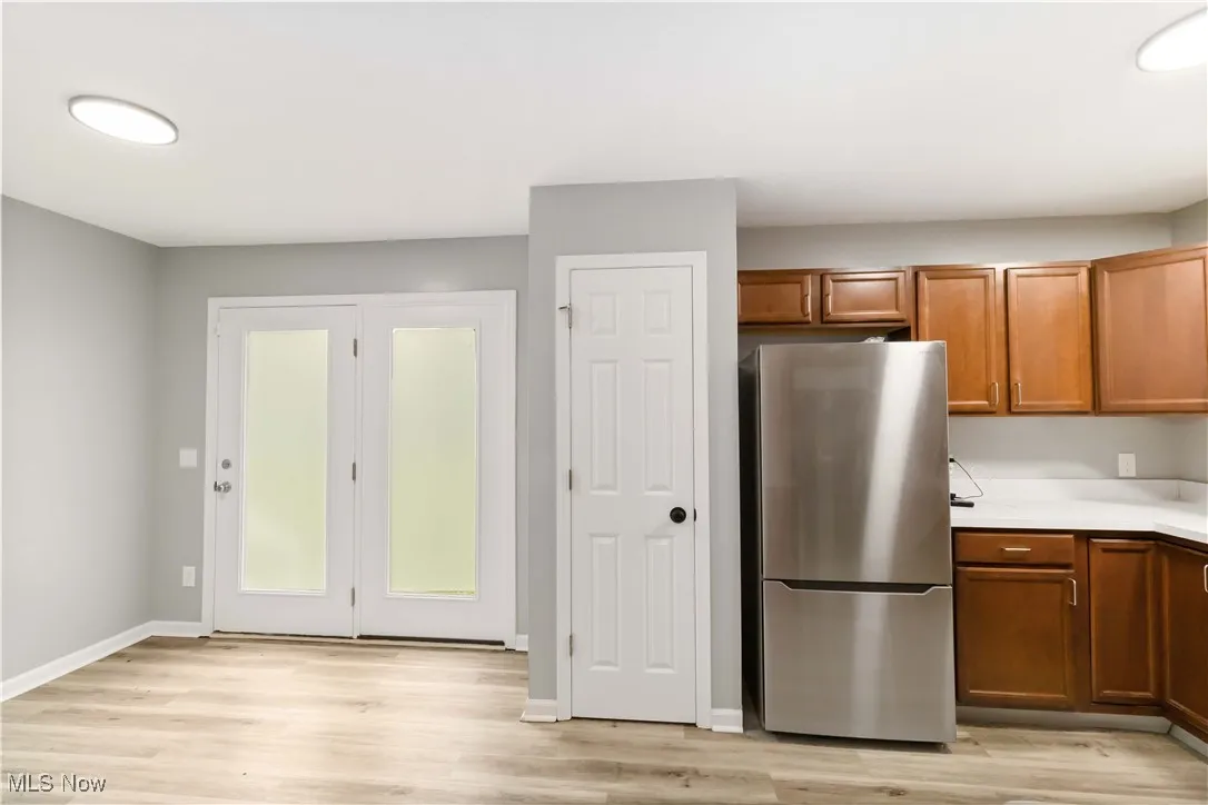 Kitchen featuring freestanding refrigerator, light countertops, brown cabinetry, and light wood-style floors