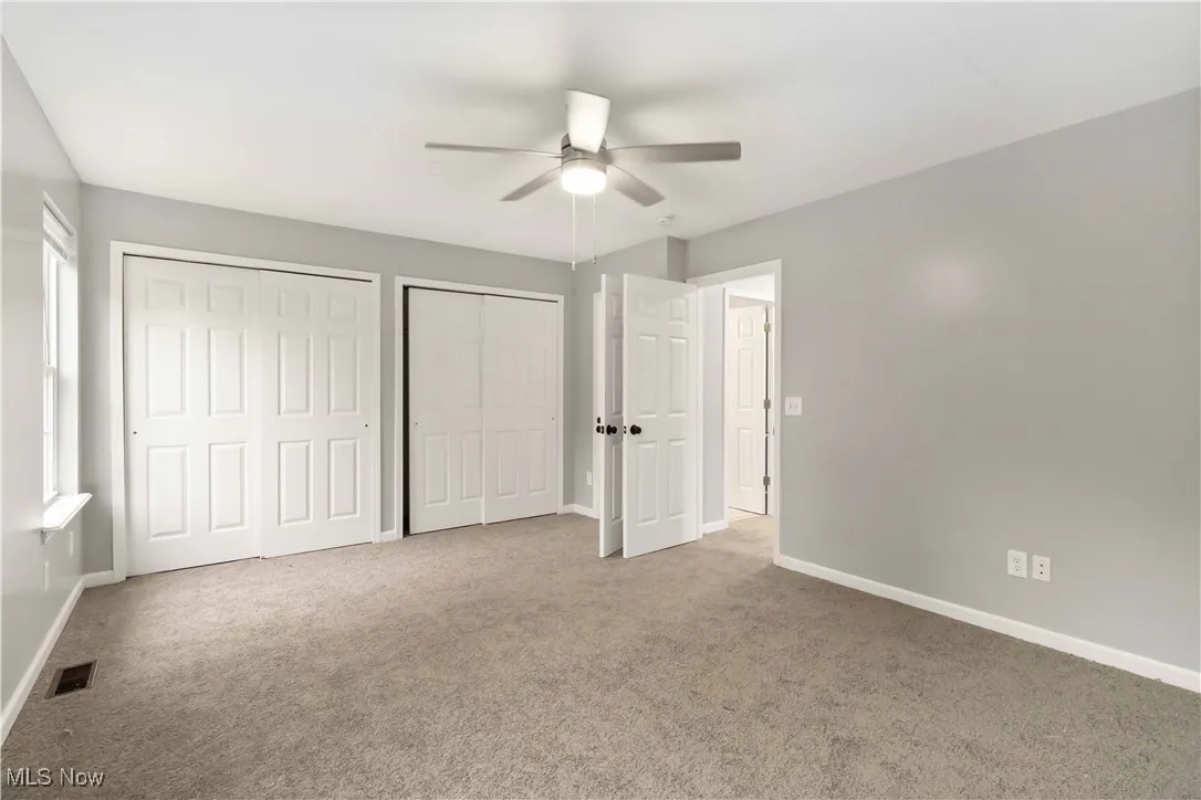 Unfurnished bedroom with multiple closets, carpet flooring, and ceiling fan