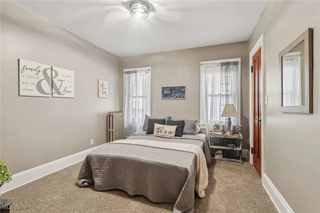 Carpeted bedroom with radiator and baseboards