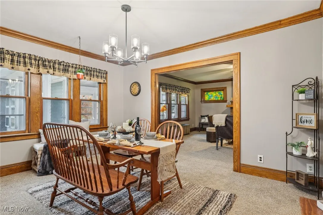 Dining area featuring crown molding, a chandelier, and carpet