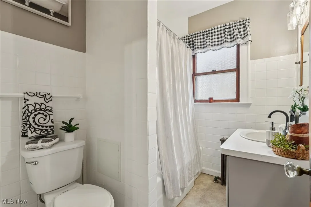 Full bathroom featuring vanity, tile walls, and a shower with curtain