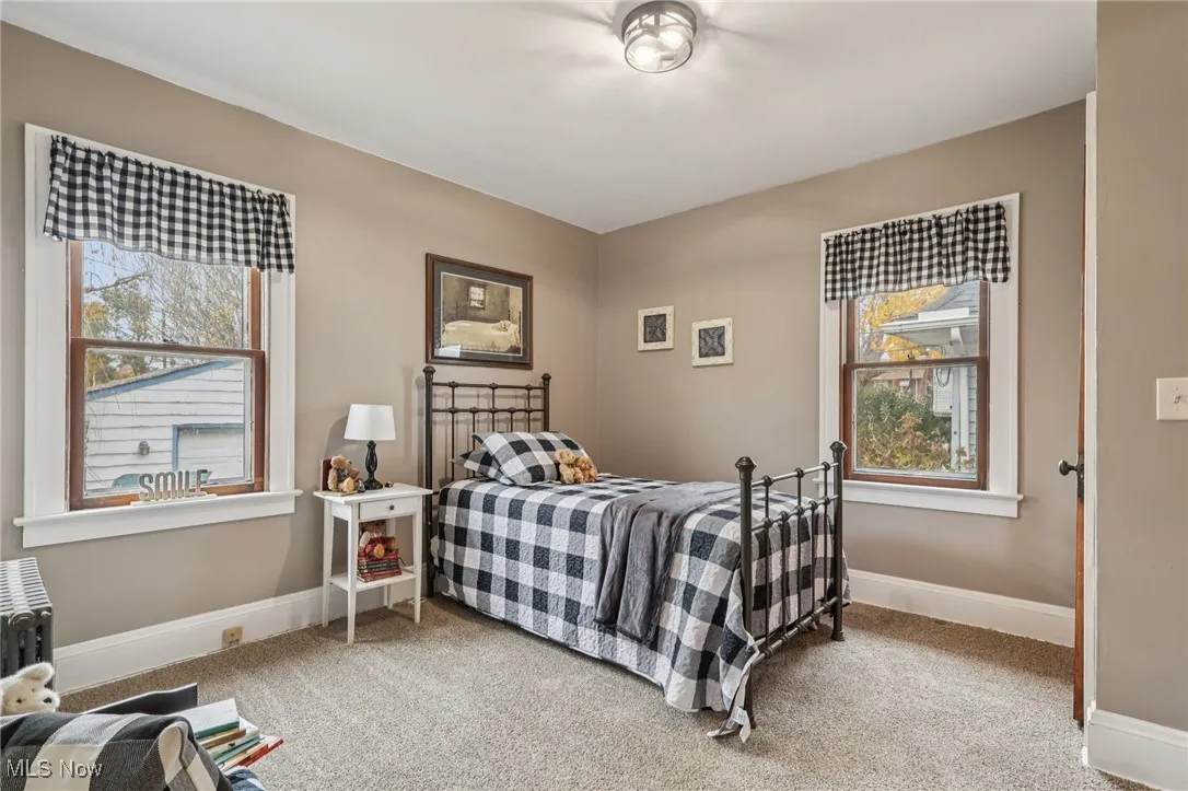 Bedroom featuring light colored carpet and multiple windows