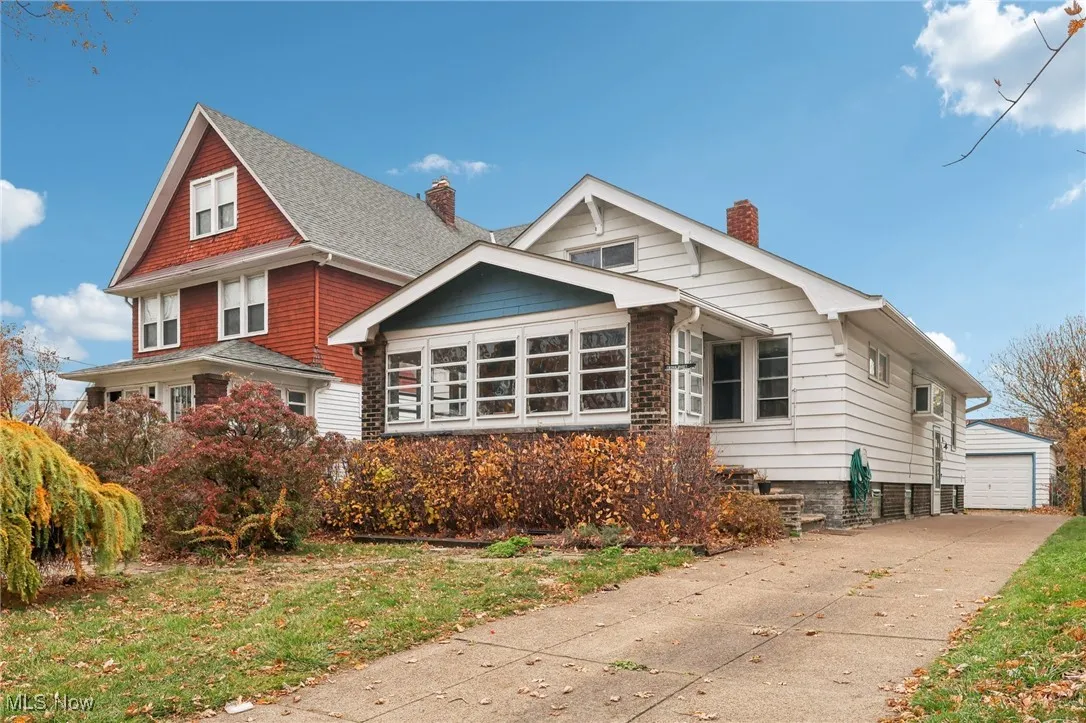Bungalow-style house featuring an outbuilding, a chimney, a front yard, a detached garage, and concrete driveway