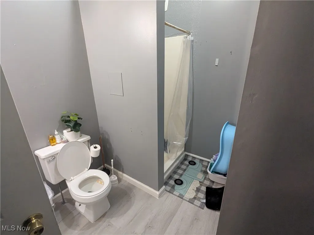 Bathroom with a shower stall and light wood-type vinyl flooring