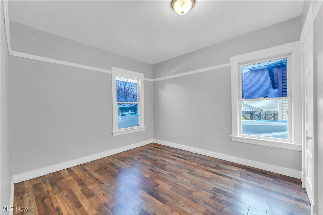 Empty room featuring dark wood-style floors and baseboards