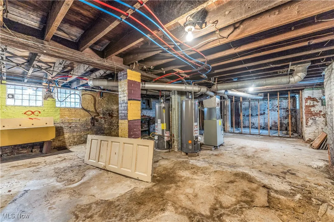 Basement featuring water heater, heating unit, and electric panel