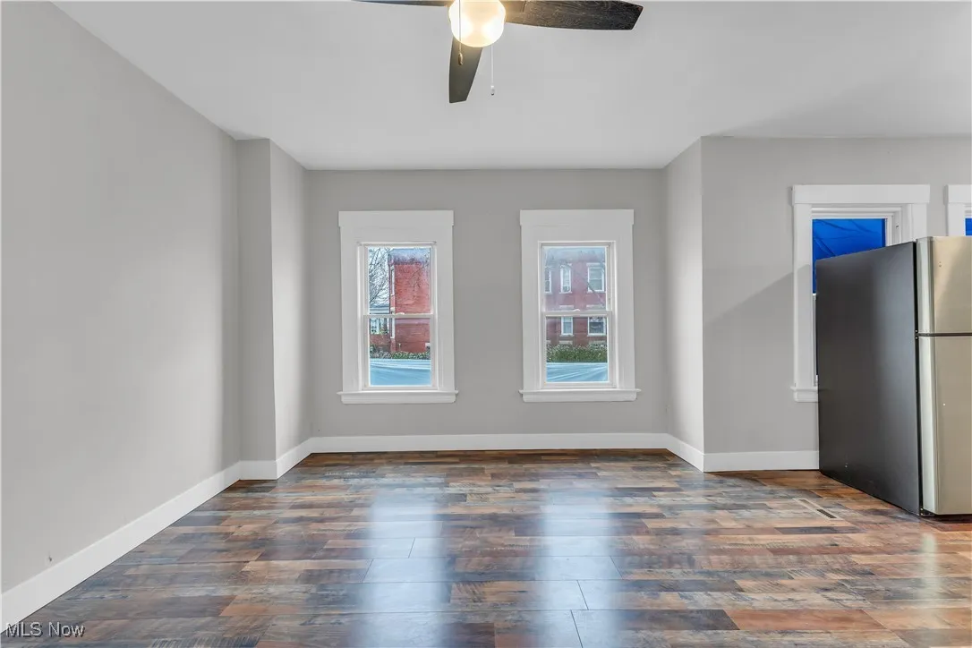 Unfurnished room featuring dark wood-style flooring and a ceiling fan