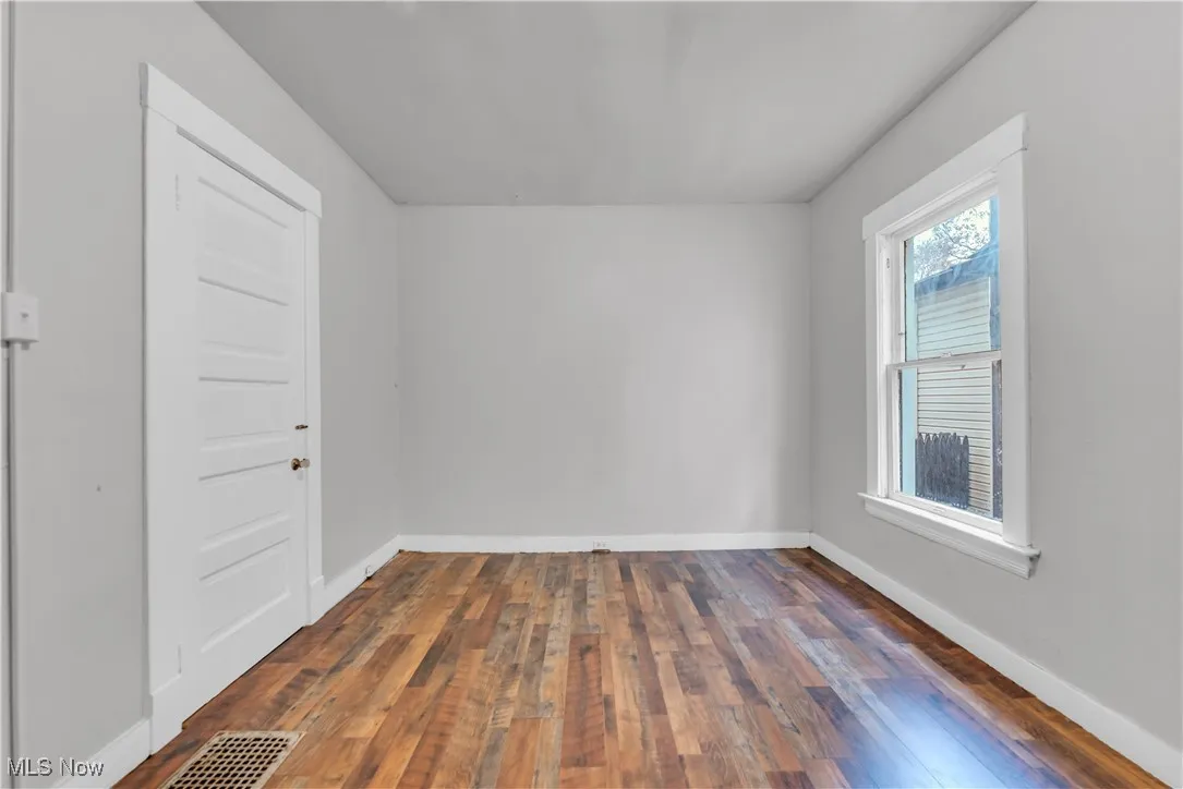 Unfurnished room featuring dark wood-style floors and baseboards