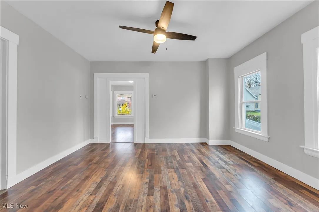 Unfurnished room with dark wood-type flooring and ceiling fan