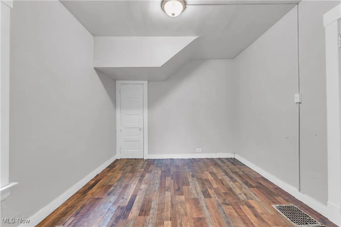 Bonus room with dark wood-style flooring and baseboards