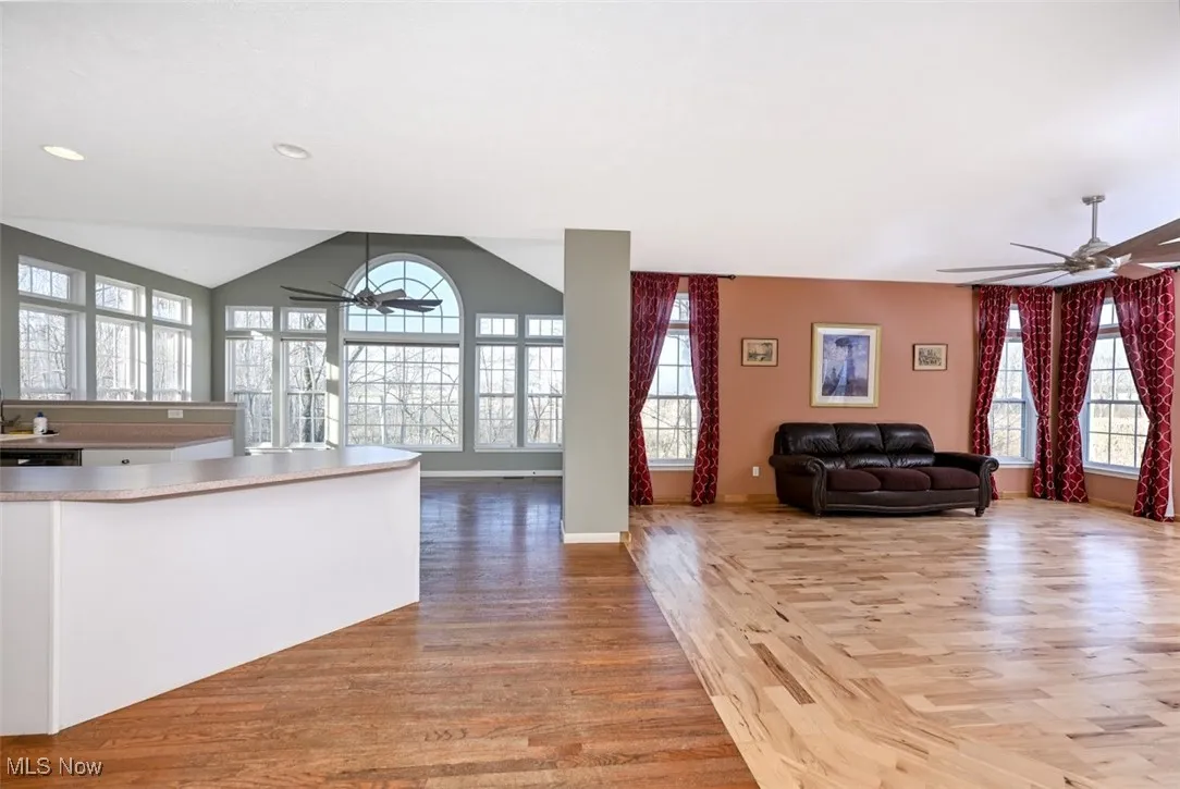 Kitchen featuring a ceiling fan, open floor plan, light wood-style flooring, plenty of natural light, and vaulted ceiling