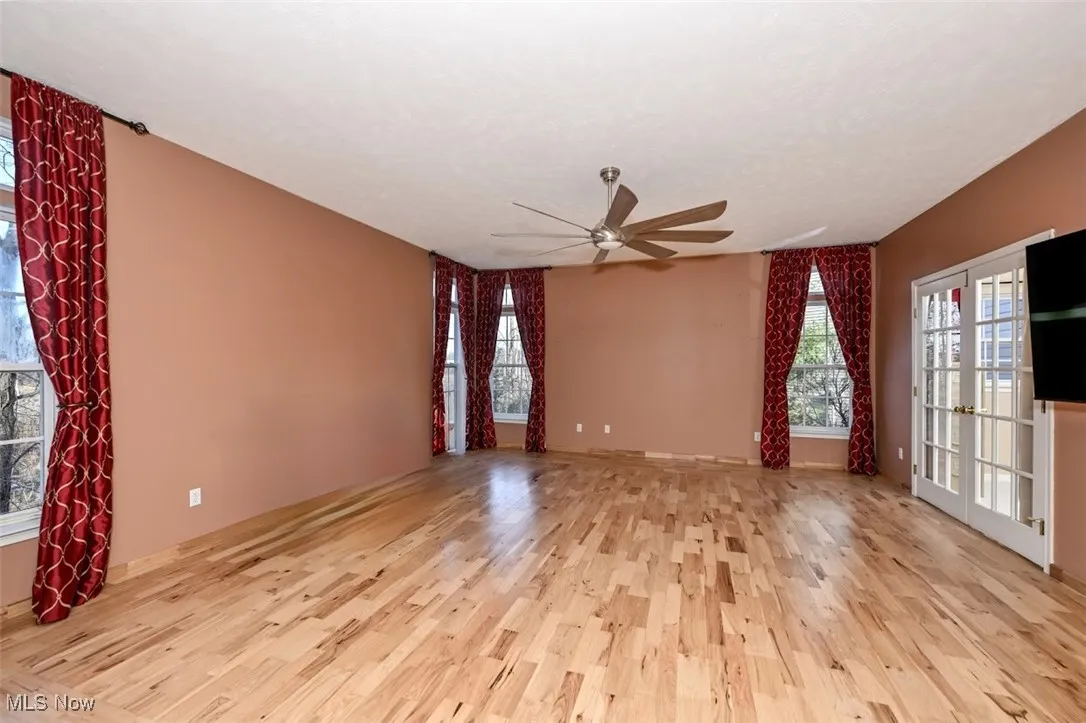 Empty room with french doors, light wood finished floors, and a ceiling fan