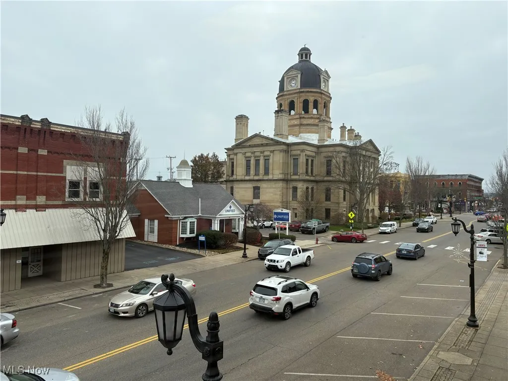 View of asphalt street featuring sidewalks, curbs, and street lighting