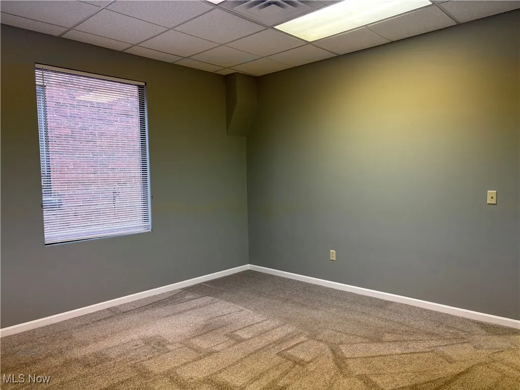 Empty room with a drop ceiling and carpet