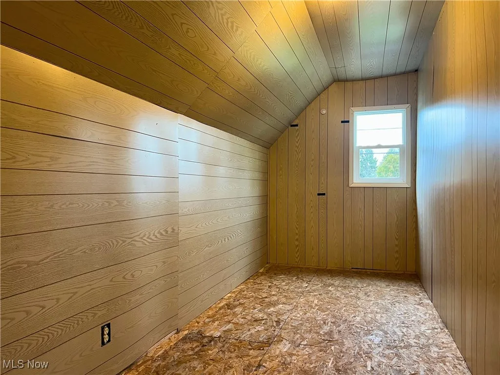 Additional space with wooden walls, vaulted ceiling, and wood ceiling