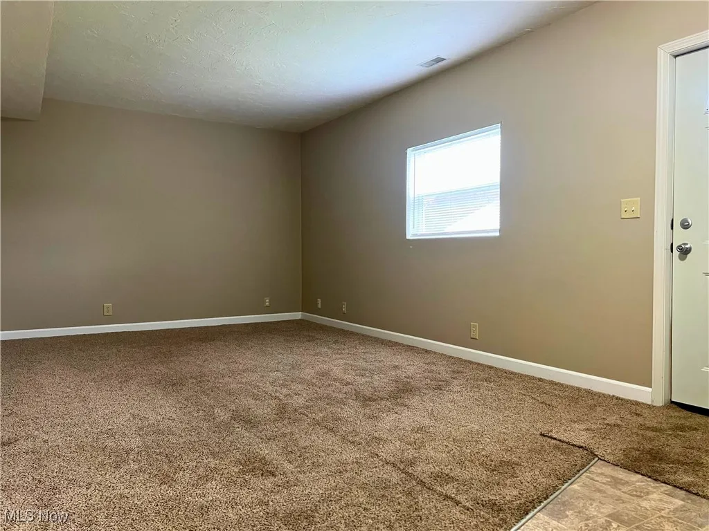 Unfurnished room featuring light colored carpet and a textured ceiling