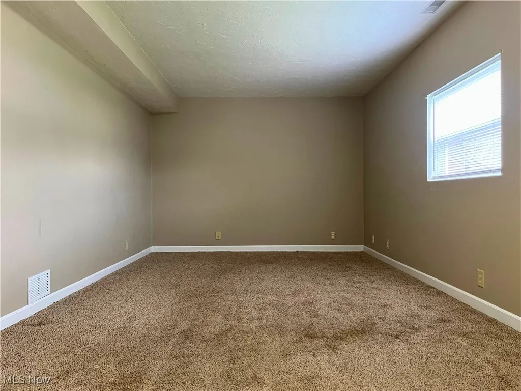 Unfurnished room  with light colored carpet and a textured ceiling