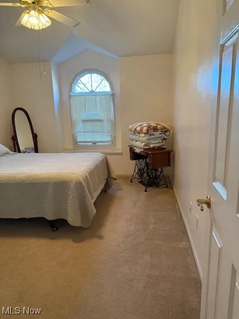 Carpeted bedroom featuring ceiling fan and baseboards