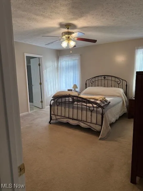 Bedroom featuring light carpet, a textured ceiling, and a ceiling fan