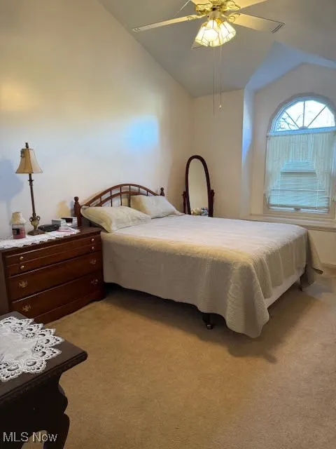 Bedroom with light colored carpet, lofted ceiling, and a ceiling fan