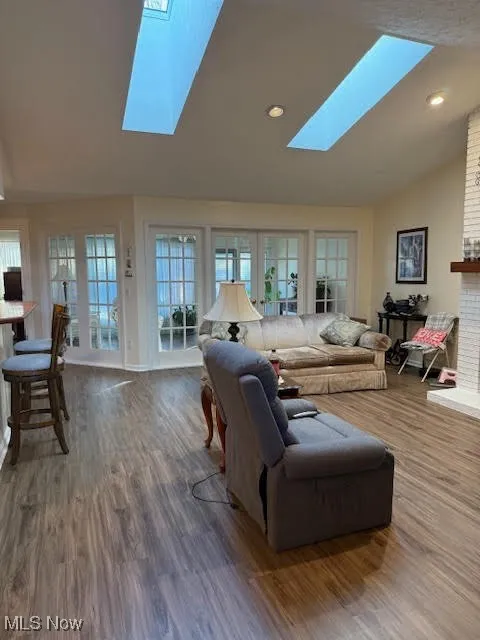 Living area with lofted ceiling, dark wood finished floors, a skylight, and recessed lighting