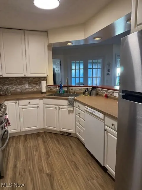 Kitchen featuring white cabinetry, appliances with stainless steel finishes, dark wood finished floors, and tasteful backsplash