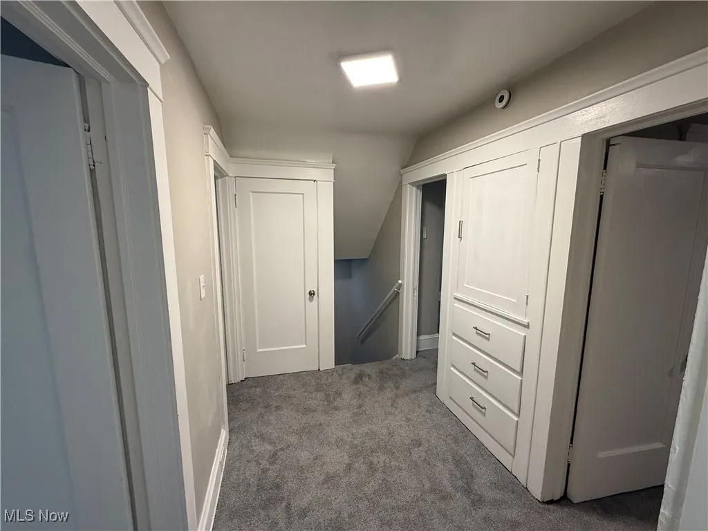 Hall featuring an upstairs landing and dark colored carpet