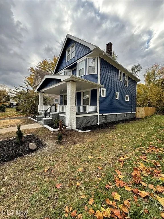View of side of home featuring covered porch and a chimney